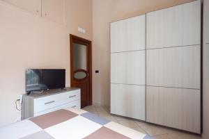1 dormitorio con un gran armario blanco y TV en SpaccaNapoli Home, en Nápoles