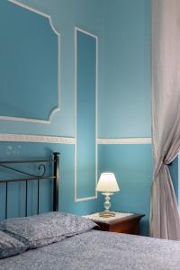 um quarto com paredes azuis e uma cama com um candeeiro em SpaccaNapoli Home em Nápoles