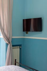 a bedroom with a blue wall with a curtain and a television at SpaccaNapoli Home in Naples
