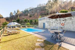 a patio with a table and an umbrella and a pool at Casa de Balinhas - Gerês in Cova