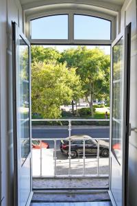 una puerta abierta a un balcón con vistas a un coche en Casa St Yves - Sunny flat in Setúbal on Av Luisa Todi, en Setúbal