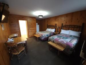 1 dormitorio con 2 camas, escritorio y mesa en Outdoorsman Motel, en Wawa