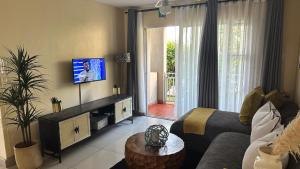 ein Wohnzimmer mit einem Sofa und einem TV in der Unterkunft KADESE Holiday North Beach Durban in Durban