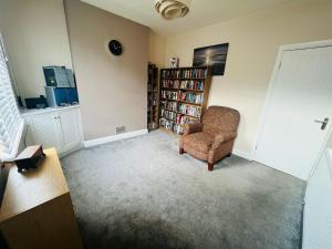 a living room with a chair and a book shelf at Cozy One bedroom house with garden in Luton in Luton
