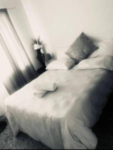 een bed met witte lakens en kussens in een slaapkamer bij Zagorski’s Bed and breakfast in Bloubergstrand
