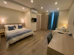 a bedroom with a bed and a couch and a tv at Aquae Stays in St Paul's Bay