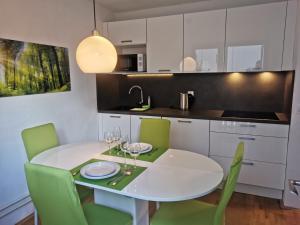 eine Küche mit einem weißen Tisch und grünen Stühlen in der Unterkunft Cosy Forest in Kranjska Gora