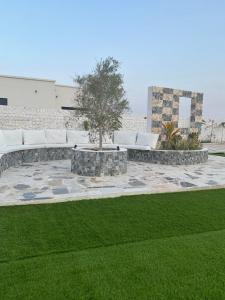 a patio with a tree and white couches and grass at Seagemfuj in Fujairah