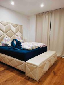 a bedroom with a bed with a large headboard and a bench at XuBa ApartmentRooms I Wien Messe Prater I Küchenzeile in Vienna