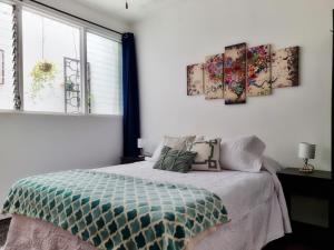 a bedroom with a bed and two paintings on the wall at Casa Jardin del Mango in San José