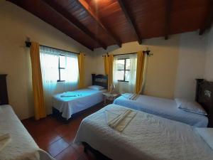 a bedroom with two beds and a window at Hotel del Bosque in Panajachel