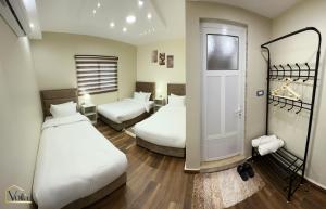 een hotelkamer met 2 bedden en een deur bij Petra Voila in Wadi Musa