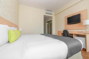 um quarto de hotel com uma cama e uma televisão de ecrã plano em Del Prado Hotel em Lima