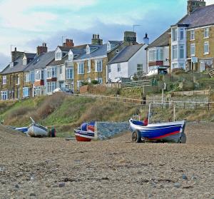 three boats sitting on the beach in front of houses at SMUGGLERS HATCH in Marske-by-the-Sea
