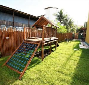 a wooden bench with a solarium in a yard at Condomínio Velas do Porto in Porto De Galinhas