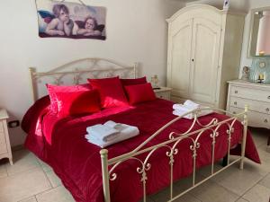 a bedroom with a bed with red sheets and red pillows at Residenza Di Nonna Giulia in Locorotondo