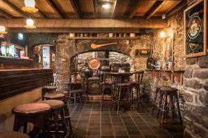 um bar com bancos e uma parede de pedra em The Garrandarragh Inn em Mullinavat