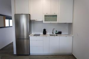 La cuisine est équipée de placards blancs et d'un réfrigérateur en acier inoxydable. dans l'établissement Apartamentos El Mirador de la Janda, à Benalup-Casas Viejas
