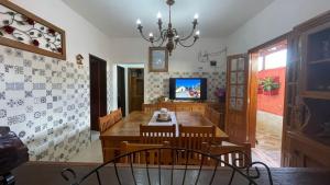 uma sala de jantar com uma mesa e uma televisão em Pouso Da Mari em Tiradentes