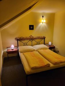 a bedroom with a bed with yellow sheets and two lamps at Penzion El Camino in Štúrovo