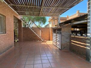 un patio al aire libre con toldo y pared de ladrillo en Departamentos Riosierras en Alta Gracia