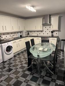 The Farm House Modern spacious 2 bedroom home at Tong road Leeds perfect for contractors free secure parking في Stanningley: مطبخ مع طاولة وغسالة ملابس
