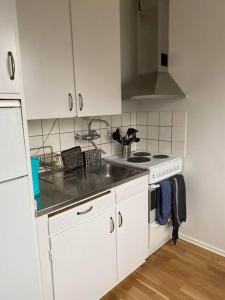 a white kitchen with a sink and a stove at A charming central one room apartment. in Malmö
