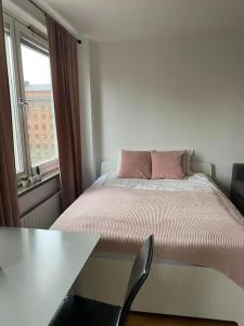 1 dormitorio con cama, mesa y ventana en A charming central one room apartment., en Malmö