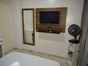 1 dormitorio con TV de pantalla plana y ventilador en Kitnet calma, en São José