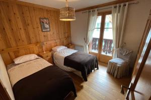 sypialnia z dwoma łóżkami, krzesłem i oknem w obiekcie Large apartment in Chamonix - close to the slopes w Chamonix-Mont-Blanc