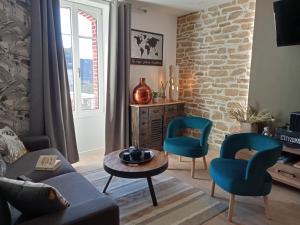 sala de estar con sofá, 2 sillas y mesa en appartement topaze en Concarneau