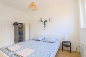 um pequeno quarto branco com uma cama e uma mesa em Appartement Familial - Avec Parking Privé Gratuit em Arras