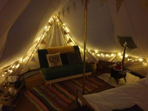 a room with a tent with a couch and lights at 6m Emperor tent near Whitby with log burner in Liverton