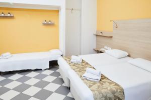 a room with two beds and a checkered floor at Klonos Anna in Egina