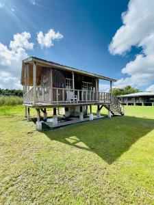 a house with a deck on a grass field at Lamanai Riverside Retreat in Orange Walk