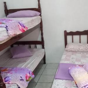 2 literas en una habitación con almohadas moradas en Cantinho Jóia, en Aparecida