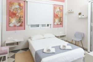 a white bedroom with two beds and a chair at Klonos Anna in Egina