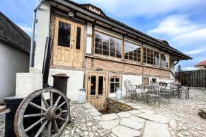 an old wooden house with a wheel in front of it at Michelsberger Haus in Cisnadioara