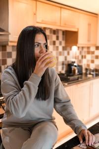 a woman sitting in a kitchen eating a hamburger at West End Escape - Prime Location in Glasgow