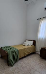 Cama en habitación con pared blanca en Casa Isa en San Juan