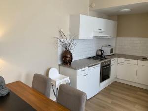 een keuken met witte apparatuur en een tafel en stoelen bij Fisherman's House by Hofstad Hotels in Scheveningen