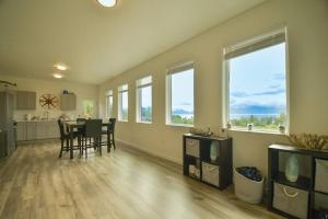 een woonkamer met een tafel, stoelen en ramen bij Rockfish Retreat at Kachemak Bay Kabins in Homer