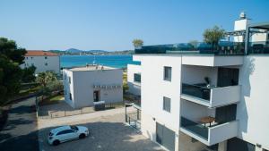 a white building with a car parked in front of it at Olive Balcony Vodice-Srima in Srima