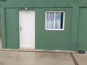 un edificio verde con una puerta blanca y una ventana en Lau departamentos en Concordia