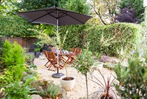 an umbrella in a garden with a table and chairs at Glensanda - By Luxury Apartments in Cheltenham