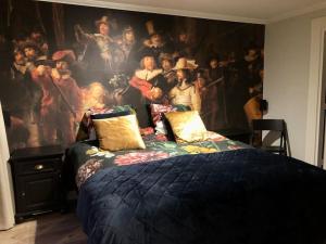 een slaapkamer met een groot schilderij aan de muur bij Voorsterstaete former barn, including jacuzzi in Voorst