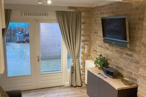 a living room with a tv on a brick wall at Voorsterstaete former barn, including jacuzzi in Voorst