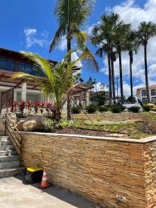 un mur de retenue devant un bâtiment planté de palmiers dans l'établissement Eco Resort Quinta Santa Bárbara, à Pirenópolis