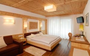 a bedroom with a large bed and a couch at Hotel Interski in Santa Cristina Gherdëina