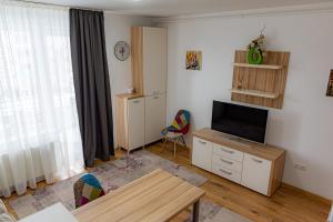 un salon avec une télévision et une table dans l'établissement Pastel Apartments, à Braşov